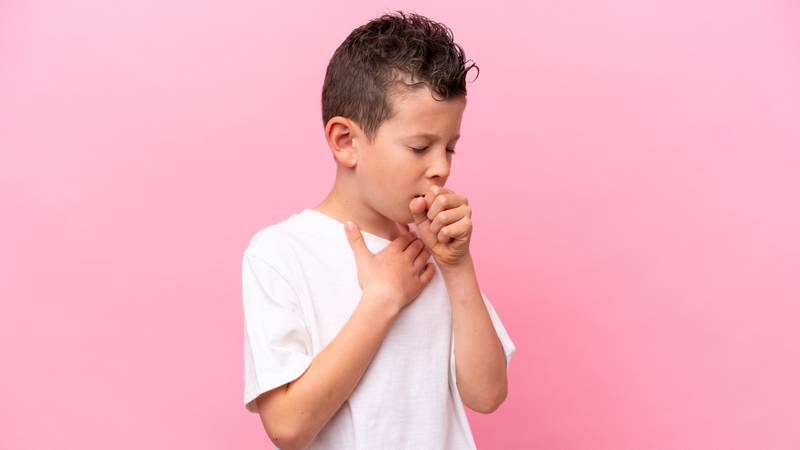 boy isolated on pink background coughing a lot