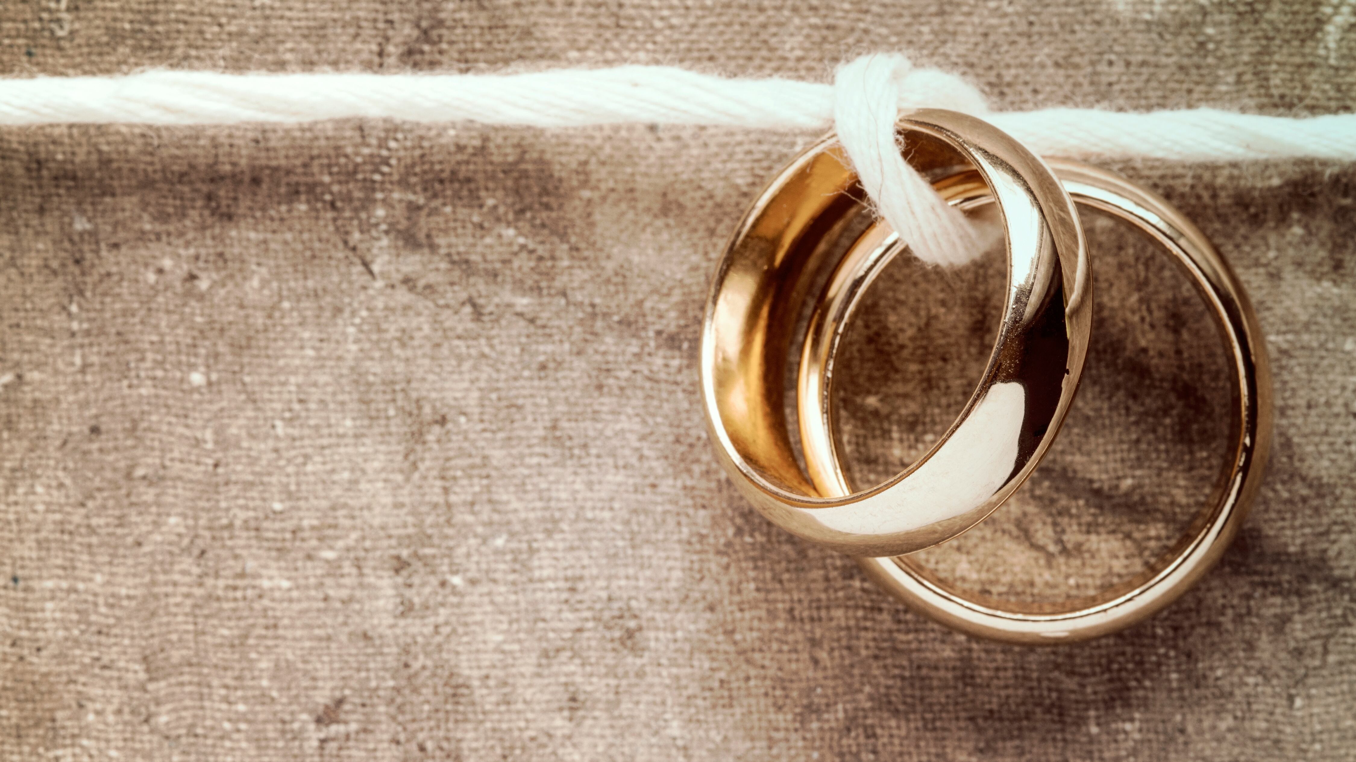 Wedding rings hanging on rope over a canvas background